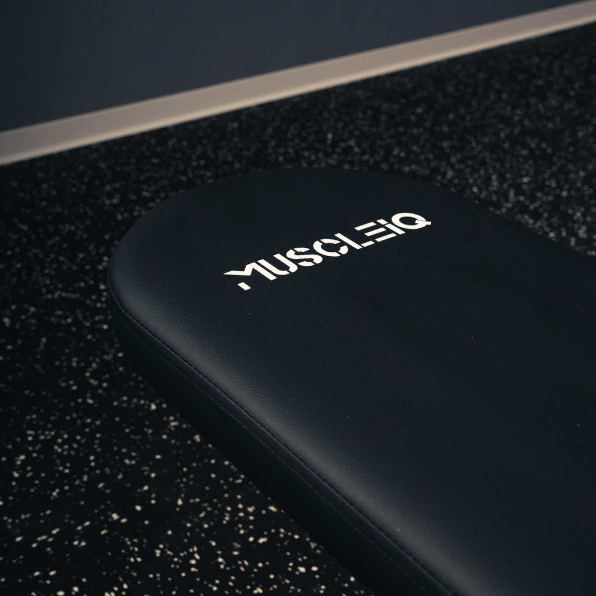 Close-up of the black padded backrest and white MUSCLEIQ logo on the adjustable weight bench