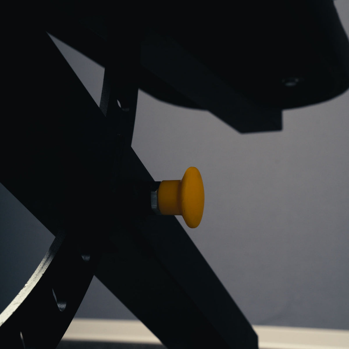 Close-up of the yellow adjustment knob beneath the seat of the MUSCLEIQ adjustable weight bench