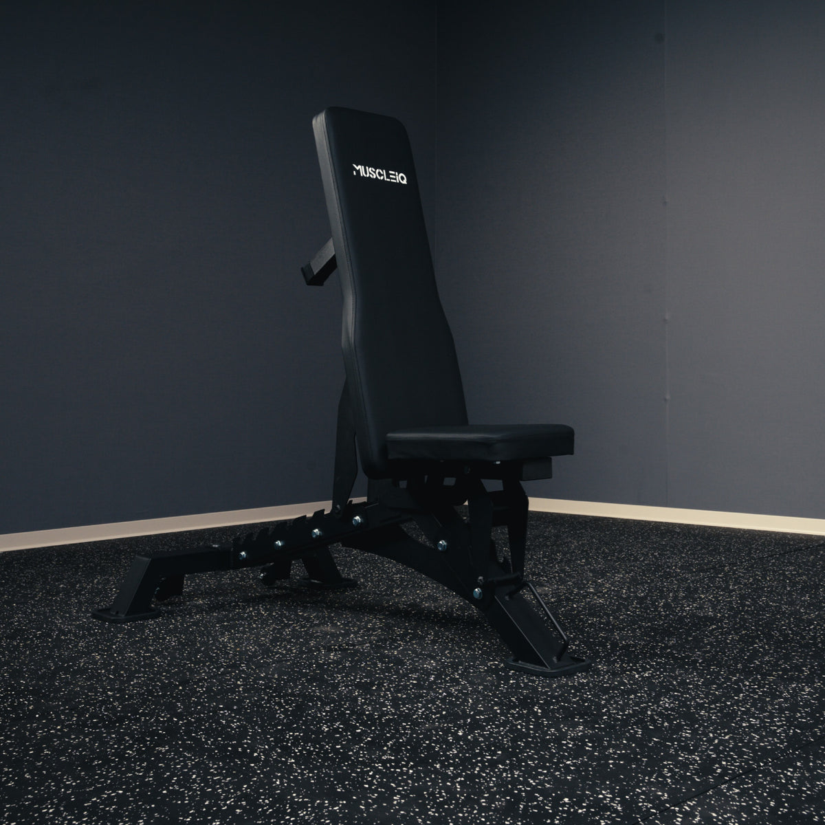 MUSCLEIQ tri-legged commercial weight bench with backrest in a steep incline position on rubber gym flooring
