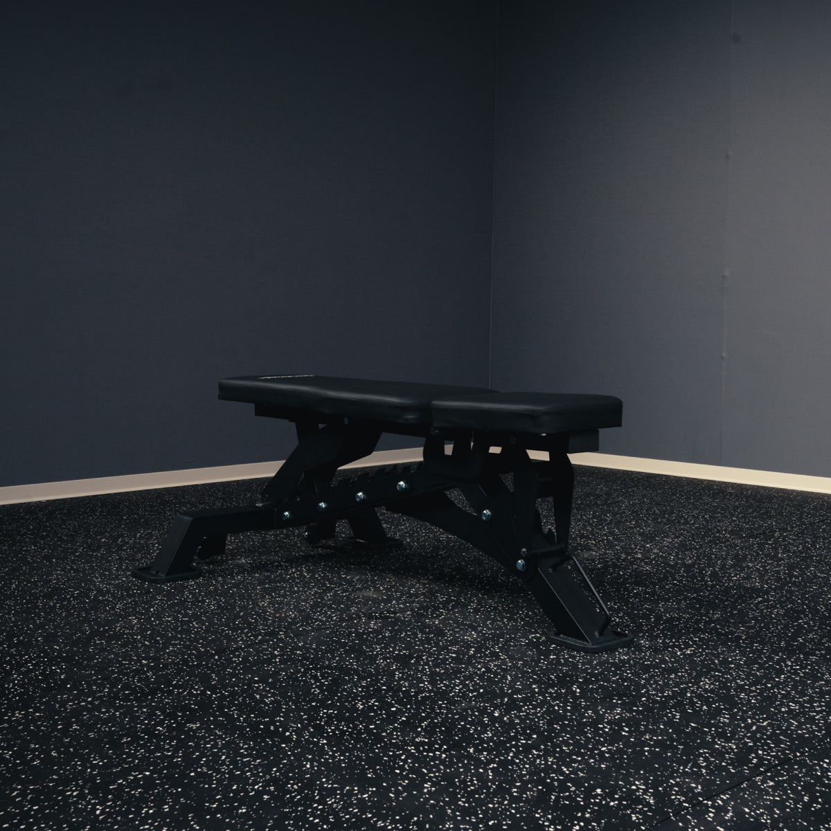 MUSCLEIQ tri-legged commercial weight bench in the flat position on rubber gym flooring