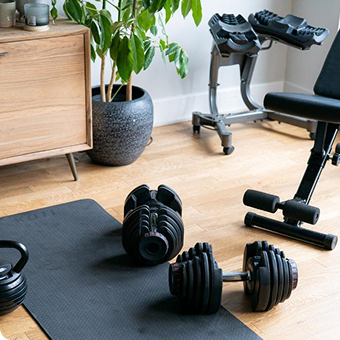 Pair of adjustable dumbbells on a gym mat in a home gym